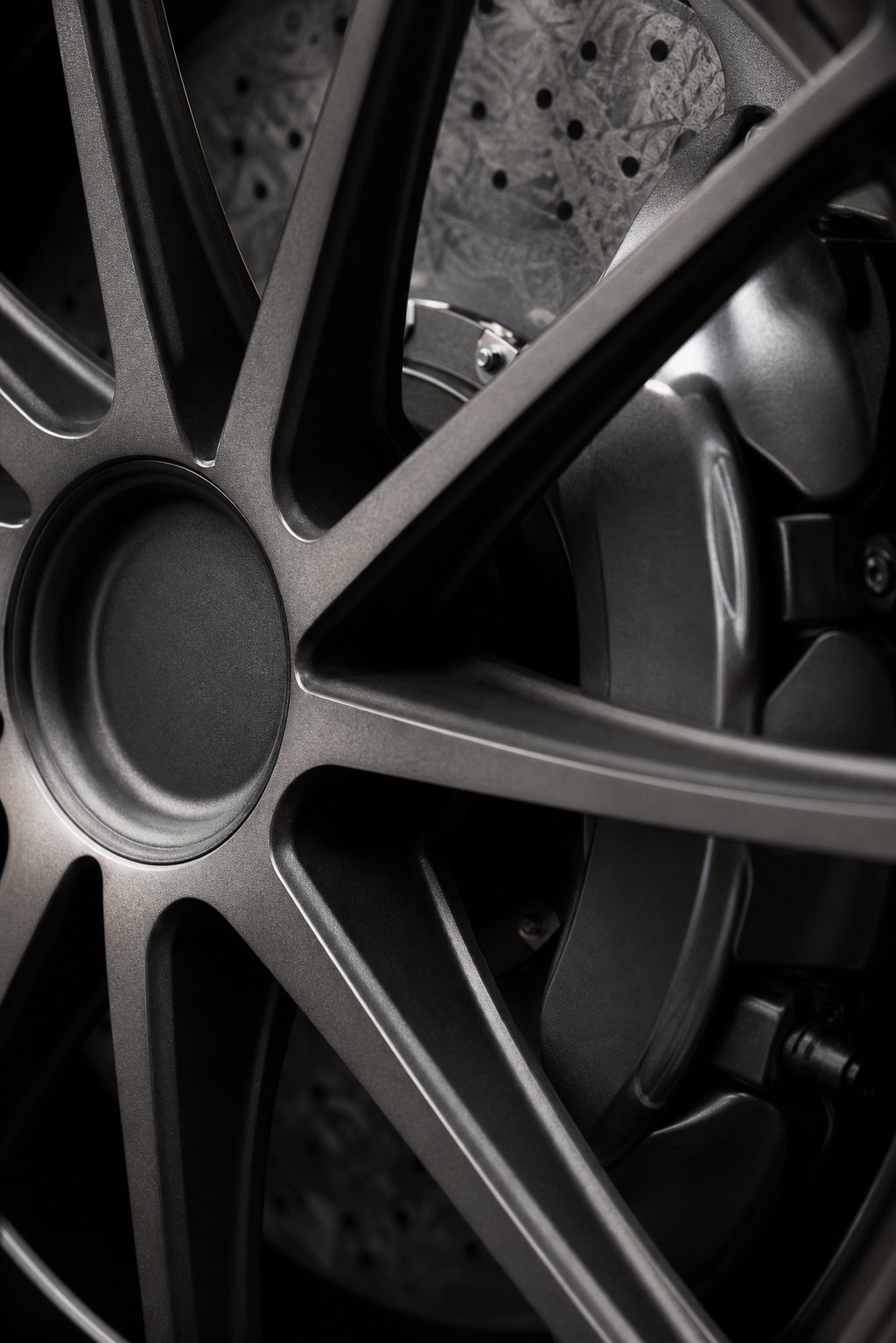 Close-up of a forged alloy wheel with a drilled carbon-ceramic brake disc and caliper visible between the spokes